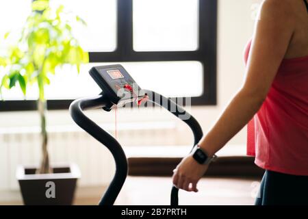 Schöne blonde kaukasische Sportlerin, die Übungen mit elastischem Band im Wohnzimmer zu Hause macht Stockfoto