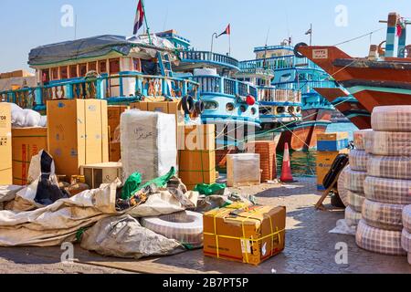 Dubai, VAE - 31. Januar 2020: Traditionelle arabische Dhow-Boote und verschiedene Waren auf Pier in Deira in Dubai, Vereinigte Arabische Emirate Stockfoto