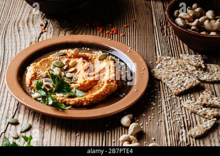 Gesunder Snack, Gourmet-Bad. Linsenhummus mit Cashews, Sesamsamen und Sonnenblumensamen auf rustikalem Holztisch Stockfoto