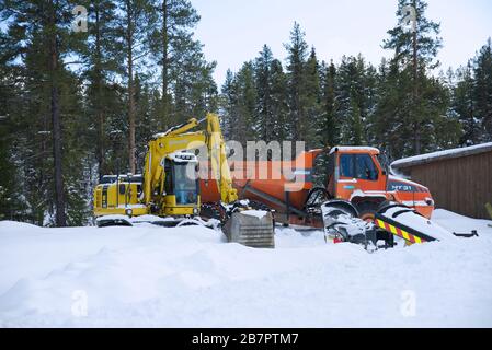 Doosan Moxy MT 31 Dump Truck und Komatsu PW 148 Excavator im Schnee Stockfoto