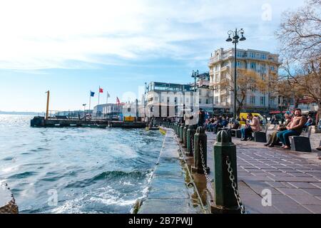 Ortakoy (Türkisch:Ortaköy) Platz in Istanbul Türkei, Foto des Stadtzentrums. Stadtlandschaft und Blickkonzept. Die Menschen sitzen auf Bänken am Meer Stockfoto