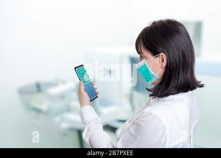 Frau in einem Krankenhauslabor hält ein Telefon mit den Ergebnissen eines Patienten, der positiv für ein Corona-Virus-Konzept ist Stockfoto