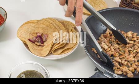 Traditionelle mexikanische Küche, Maistacos mit Hühnerfleisch und Gemüse schließen sich auf einem Küchentisch an Stockfoto