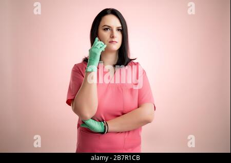 Porträt der schönen Frau Doktor mit Stethoskop mit pinkfarbenen Schruppen, Gespräch auf Handy, Smartphone posiert auf einem pink isolierten Backround. Stockfoto