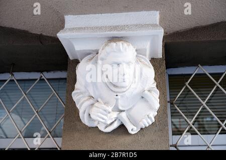 Elemente architektonischer Verzierungen von Altbauten, weißer Gipsfigur und Gesicht des Menschen. Ein Mann hält Pergament und Stift zum Schreiben. Das Element von de Stockfoto