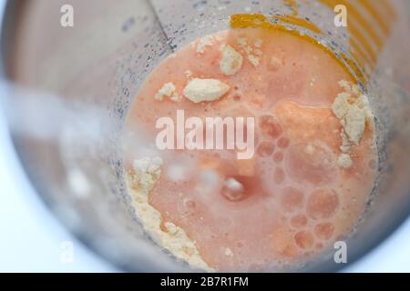 Wasser wird in eine Mixer-Schüssel gegossen, um einen Cocktail zu machen. Eiweißschütteln in einem Schüttler. Pulversport Ernährung. Stockfoto