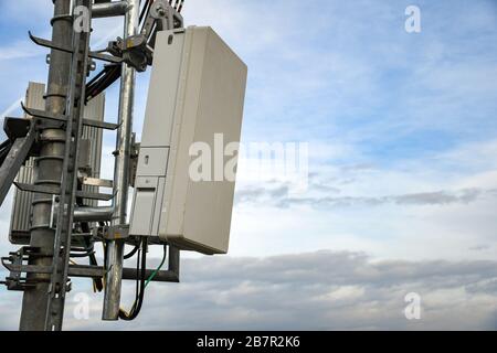 5G neue Funk-Telekommunikationsnetzantenne auf einem Metallpol, die starke Signalwellen von der Dachspitze in der Großstadt liefert Stockfoto