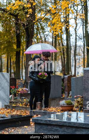 Mann und Frau auf einem Friedhof mit Blumen Stockfoto