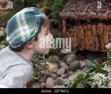 Junger Junge mit blauen Augen, mit einem britischen, pflasterigen flachen Hut, der mit Neugier und Wunder aussieht. Stockfoto