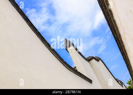 Blick in die Skyward in einer hutong Gasse zwischen zwei weißen traditionellen Betonmauern und Fliesen, was der typische Baustil von Ming und Q ist Stockfoto