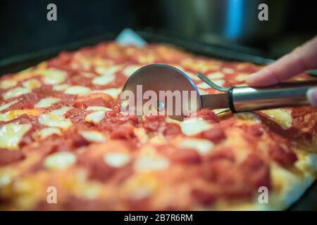Schneiden von Scheiben hausgemachter Pizza Stockfoto