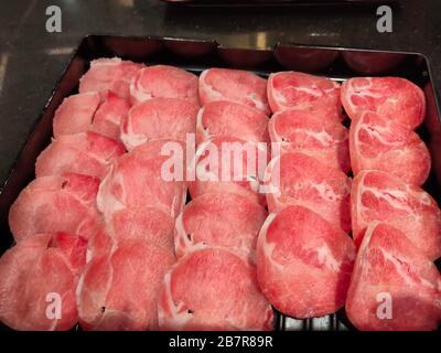 Das frische Schweinefleisch, das für japanischen heißen Topf auf schwarzem Teller geschnitten wurde Stockfoto