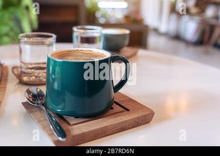 Nahaufnahme von grünen Tassen heißen Kaffees und Gläsern Wasser auf dem Tisch im Café Stockfoto