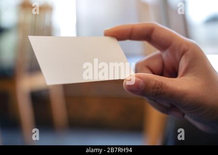 Eine Hand, die weiße leere Visitenkarte mit verschwommenem Hintergrund enthält Stockfoto