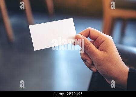 Eine Hand, die weiße leere Visitenkarte mit verschwommenem Hintergrund enthält Stockfoto