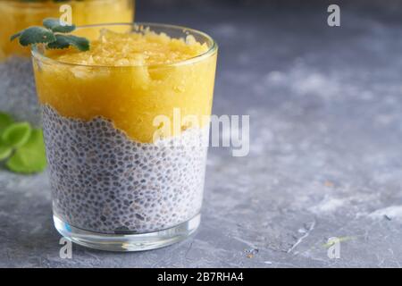 Chia Pudding mit Mango und Minze in Glas auf grauem Tisch Kopierraum Stockfoto