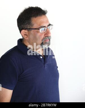 Ein indianischer Mann mit einem Ziegenbart in einem Studio vor weißem Hintergrund. Brille tragen und von der Kamera wegschauen. Stockfoto