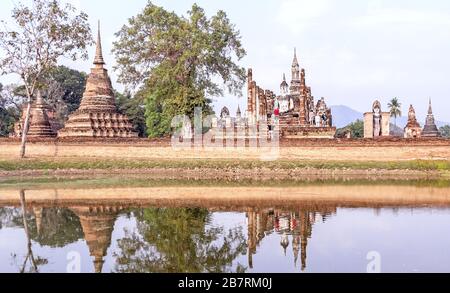 Gruppe von Touristen in einem alten buddhistischen Tempelkomplex in Sukhothai, Thailand; Reise- und Tourismuskonzept Stockfoto