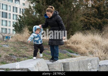 Eine Mutter half ihrer Tochter dabei, sich über einige große Steine im Hudson River Park zu klauen. Der Park verläuft entlang des Hudson River zwischen Chambers Street und MID Stockfoto