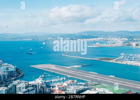 Blick auf Frachtschiffe aus dem Felsen von Gibraltar und Blick auf die Start- und Landebahn für Flugzeuge, den spanischen Hafen von Algeciras und die britische Kolonie Gibraltar. Stockfoto