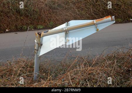 Ein Straßenschild versagt aufgrund der salzigen Luft und des schlechten Wetters mit dem Stahlpfosten, auf dem er von der korrosiven Atmosphäre weggerostet wird. Stockfoto