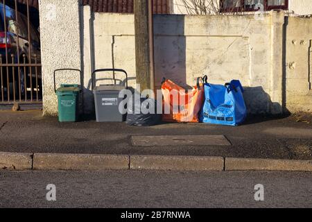 Eine Reihe von Binde- und Warnstreifen außerhalb der Bordsteinsammlung der verschiedenen Fahrzeuge, die alle verschiedenen Gegenstände sammeln sollen. Stockfoto