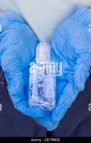 Flasche mit antibakteriellem Gel in den Händen in Schutzhandschuhen Stockfoto