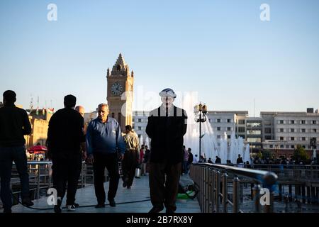 Irak, Iraq Kurdistan, Arbil, Erbil. Auf dem Park Shar laufen Männer. Im Hintergrund steht Erbil Uhr und ein Brunnen Stockfoto