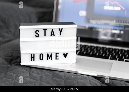 Leuchtkasten mit "Bleibe zu Hause"-Text auf Holzhintergrund. Flat-Lay-Covid-19-Angebot in Draufsicht Stockfoto