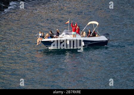 Menschen auf einem Motorboot winken zu einem Kreuzfahrtschiff, während es Santa Cruz auf Tenera verlässt Stockfoto