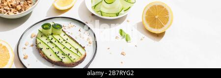 Frischer Gurken-Toast mit Samen in der Nähe von Minzblättern und Zitrone auf weißem Hintergrund, Panorama-Schuss Stockfoto