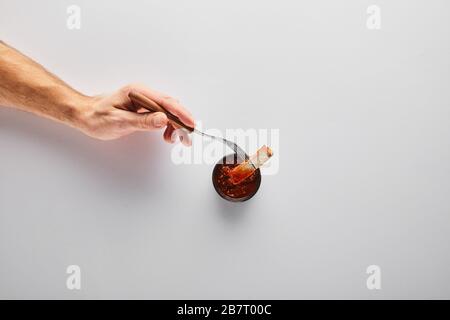 Draufsicht des Mannes, der Steakscheibe in Tomatensauce auf weißem Hintergrund legt Stockfoto