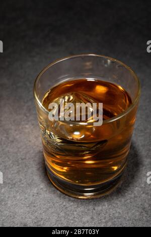 Eiswürfel aus Glas alkoholischen Getränks auf grauer Oberfläche Stockfoto