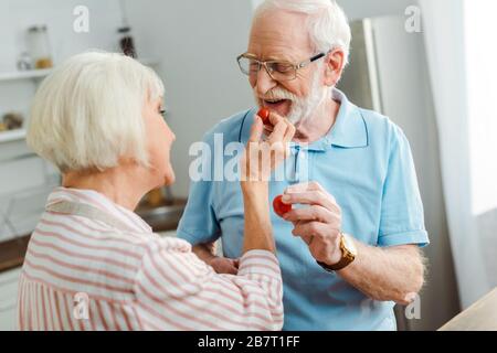 Selektiver Fokus des Senioren-Paares, das reife Kirschtomaten in der Küche hält Stockfoto