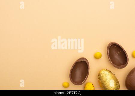 Draufsicht von Schokolade und Wachteleiern mit gelben Süßigkeiten auf beigefarbenem Hintergrund Stockfoto