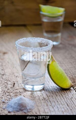 Alkoholgetränk. Silberner Tequila mit Limette und Salz auf dem Holztisch. Stockfoto