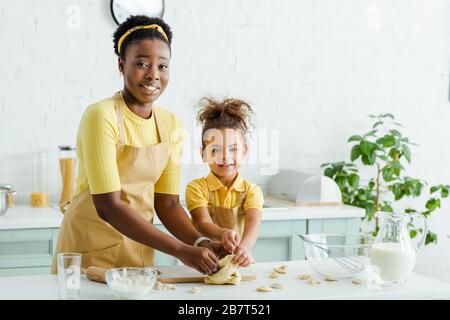 afroamerikanische Mutter in der Nähe von glücklichen Kid, die Knödel in der Küche formte Stockfoto