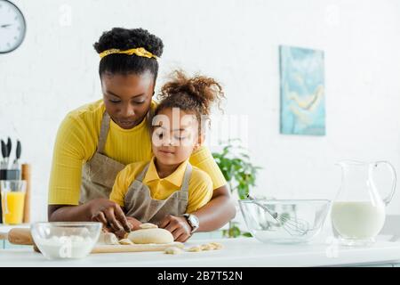 afroamerikanische Mutter in der Nähe von liebenswerten Kid, die Knödel in der Küche formte Stockfoto