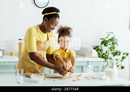 Fröhliche afroamerikanische Mutter und glückliche Kinder, die Knödel in der Küche skulptieren Stockfoto