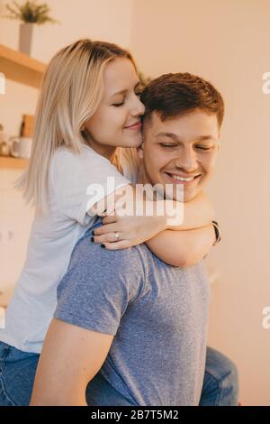 Blonde kaukasische Frau umarmt ihren Mann, während sie während der Quarantäne zusammen jubelt Stockfoto