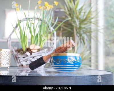 Haulerwijk - 07. märz 2020: Haulerwijk, Niederlande. Blaue und goldene indische Gesangsschale aus sieben Metallen mit einem Holzstreifer auf einem Glas Stockfoto