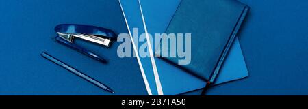 Panoramaaufnahme von Notebooks, Stift und Hefter isoliert auf blau Stockfoto