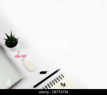 Flacher Tisch mit Blick auf die Oberseite. Arbeitsbereich mit Tastatur, Büromaterial, Stift, Topfpflanzen und Notizbuch auf weißem Hintergrund. Stockfoto