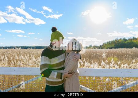 Fröhliches junges multiethnisches Paar umarmt und betrachtet sich gegen den herbstlichen Bulrush Field Stockfoto
