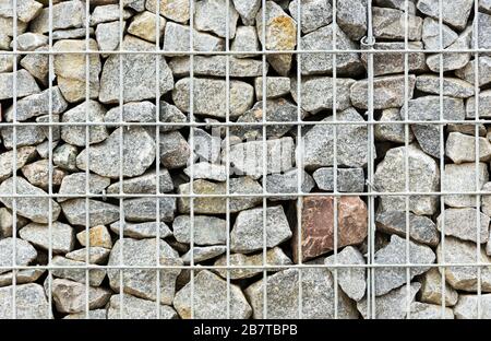 Wand aus Steinen hinter dem Gitter Stockfoto