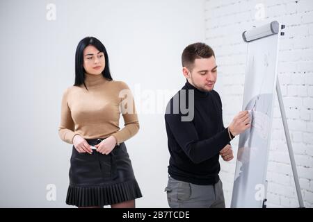 Der Typ, ein Geschäftsmann, ein Lehrer, ein Mentor, unterrichtet ein Fachmädchen, einen Schüler. Konzept des Arbeitstages Stockfoto