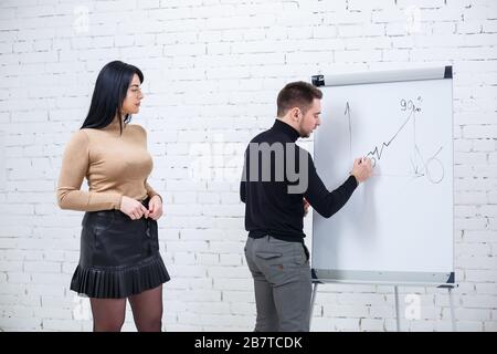 Der Typ, ein Geschäftsmann, ein Lehrer, ein Mentor, unterrichtet ein Fachmädchen, einen Schüler. Konzept des Arbeitstages Stockfoto