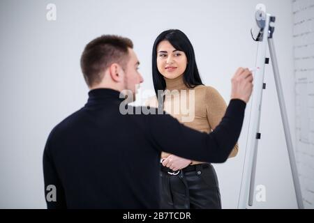 Der Typ, ein Geschäftsmann, ein Lehrer, ein Mentor, unterrichtet ein Fachmädchen, einen Schüler. Konzept des Arbeitstages Stockfoto
