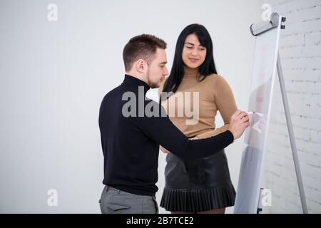 Der Typ, ein Geschäftsmann, ein Lehrer, ein Mentor, unterrichtet ein Fachmädchen, einen Schüler. Konzept des Arbeitstages Stockfoto