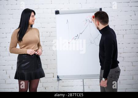 Der Typ, ein Geschäftsmann, ein Lehrer, ein Mentor, unterrichtet ein Fachmädchen, einen Schüler. Konzept des Arbeitstages Stockfoto